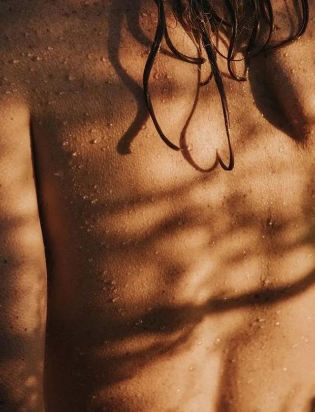 Espalda con gotas de agua y sombras de hojas
